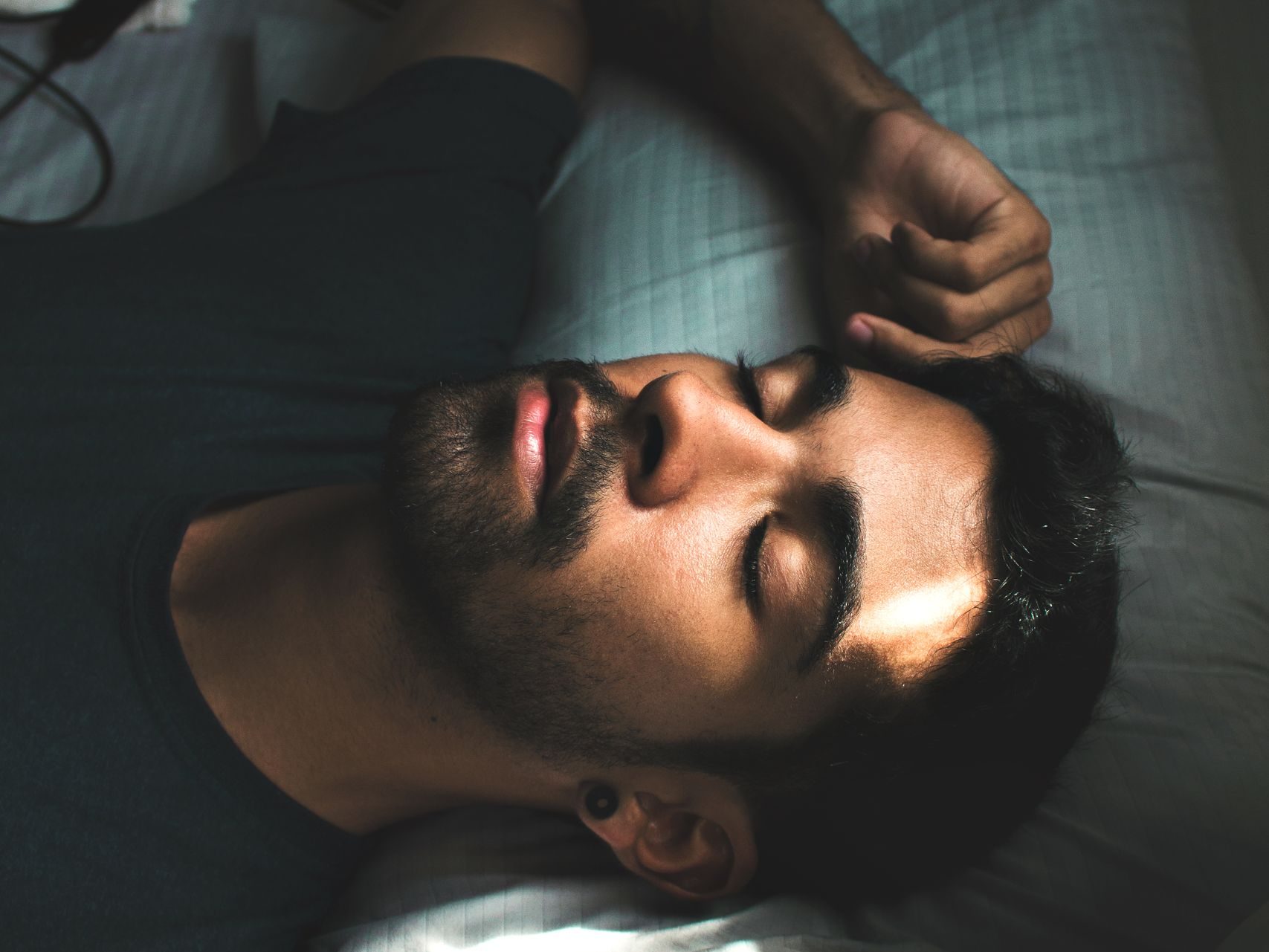A serene portrait of a young man sleeping peacefully in a sunlit bedroom setting.